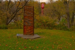 The sculpture Upriver: Ripple Marks, Allentown Formation by Heidi Wiren Bartlett stands in front of autumn trees on the Karl Stirner Arts Trail in Easton, Pennsylvania.