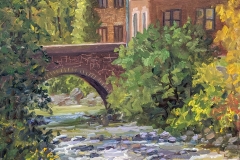 A plein air painting  by Tricia Lowry Lippert of trees and a bridge connecting to the brick buildings of the Silk complex next to the Karl Stirner Arts Trail in Easton, Pennsylvania